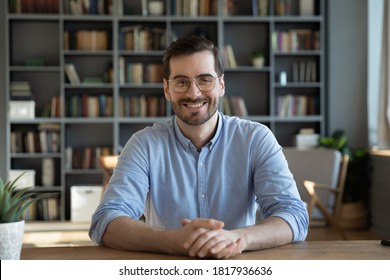 Headshot portrait of smiling 30s Caucasian millennial man in glasses sit at desk at home talk speak on video call or webcam virtual conference. Picture of happy young male in spectacles pose at table. - Shutterstock ID 1817936636