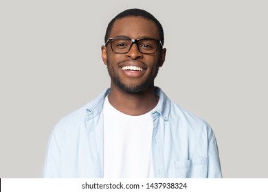 Headshot Portrait Of Smiling African American Man Wearing Glasses And Shirt Look At Camera Laughing, Happy Black Millennial Male In Spectacles Isolated On Grey Studio Background Posing For Picture