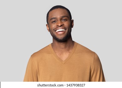 Headshot Portrait Of Smiling African American Millennial Man In Tshirt Isolated On Grey Studio Background, Happy Black Male Look At Camera Feel Satisfied Or Pleased Laughing Posing For Picture