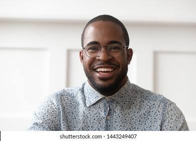 Headshot portrait of smiling african American male in glasses looking at camera talking or shooting, happy black man wear spectacles posing laugh with white toothy smile, recording video on gadget