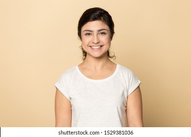 Headshot portrait of smiling millennial indian girl isolated on orange brown studio background look at camera, happy positive young ethnic woman in casual wear posing in white t-shirt showing teeth - Powered by Shutterstock