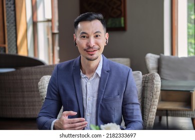 Headshot Portrait Of Smiling Young Asian Man Wearing Suit, Having Video Call Or Blogging To Internet Audience. Happy Millennial Speak Online Using Webcam Conference On Computer