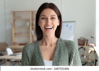 Headshot portrait of smiling young caucasian businesswoman look at camera posing in modern office, happy millennial female employee show optimism, success and motivation at work, leadership concept