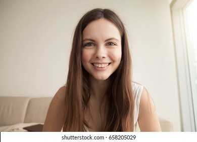 Headshot portrait of smiling young woman. Teen girl with happy facial expression looking at camera with joy, communicating with friends via internet telephony, making video call. Close up. Front view - Shutterstock ID 658205029