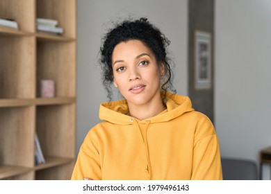 Headshot portrait of young attractive African American mixed race girl student in casual clothing hoodie posing indoors at modern living room home office looking at camera. Portrait - Powered by Shutterstock