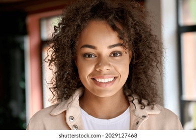 Headshot portrait of young attractive happy smiling African American mixed race ethnic girl student or professional posing indoors at modern home office looking at camera. Close up face, portrait - Powered by Shutterstock