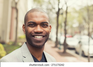 Headshot portrait of young man smiling isolated on outside outdoors background.