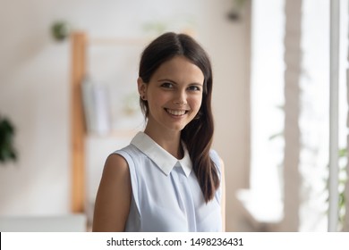 Headshot profile picture of confident young woman bank specialist or coach stand looking smiling at camera, happy positive millennial female employee or worker posing making photo, shooting for album