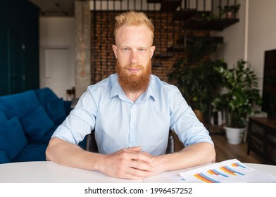 Headshot Of Redhead Businessman In Smart Casual Shirt Sis At The Desk And Looks At The Camera With Serious Face Expression, Video Meeting With Red Haired Guy, Portrait Of Male Employee In Home Office