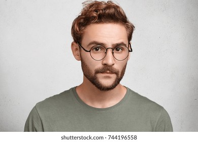 Headshot Of Serious Clever Man Professor Going To Conduct Lecture, Wears Spectacles, Waits Students. Bearded Wonk Looks Confidently, Being Sure In His Knowledge, Expresses Assertion Or Self Reliance