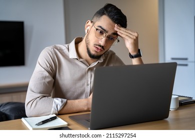 Headshot thoughtful young indian businessman or student in eyewear looking at laptop computer screen. Pensive confused man thinking of problem solution stuck with task, working online from home office - Powered by Shutterstock