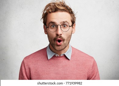 Headshot von unraven männlichen Wunder starrt durch Brillen und Open-nes Mund, emotional, hat Eile Reaktion auf hohe Preise im Geschäft, einzeln auf weißem Betonhintergrund. Überraschungskonzept
