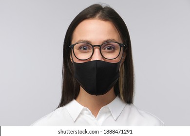 Headshot Of Young Business Woman Or Female Teacher In Glasses And Black Medical Mask, Looking At Camera With Smile, Isolated On Gray Background