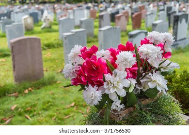 Headstones On A Graveyard In Fall With Flowers In The Foreground, In An American Cemetery