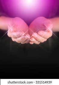 Healer with Magenta Healing Orb Energy - female holding hands in cupped position with a bright magenta colored orb  energy hovering above and sparkles around finger tips