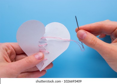 Healing Broken Heart. Hands Sewing A Broken Heart