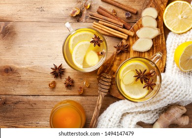 Healing ginger tea in two glass mug in scarf with lemon, honey and spices. Autumn hot drink on rustic wooden table top view.