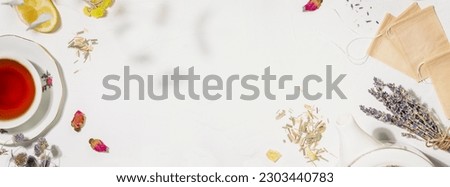 Healing herbal tea banner with wild plants and flowers. Home herbal apothecary concept. Sustainable flat lay with natural flowers and herbs, paper tea bags, cup of tea on white background. Copy space