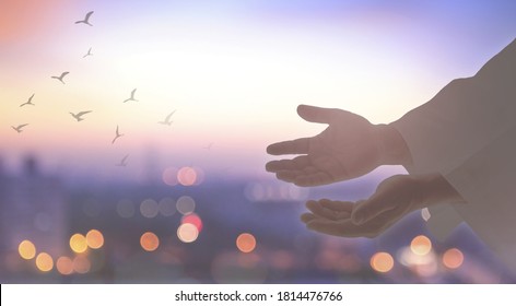 Heals concept: Silhouette Jesus Christ open spiritual hands with birds flying over blurred autumn sunset background - Shutterstock ID 1814476766