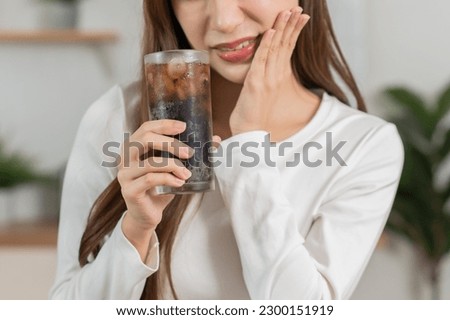 Health asian young woman, girl hand touching her mouth, suffering from toothache, decay or sensitivity cavity molar tooth or inflammation drink cold, sparkling water at home. Sensitive teeth concept.
