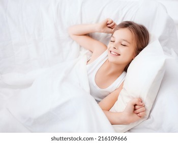 Health, Beauty And Childhood Concept - Smiling Girl Child Waking Up In Bed At Home