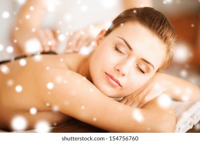 health and beauty concept - woman in spa salon with hot stones
