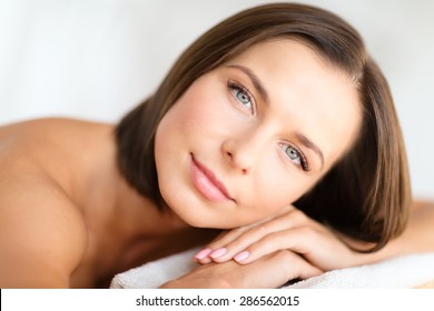 health, beauty, resort and relaxation concept - beautiful woman in spa salon lying on the massage desk