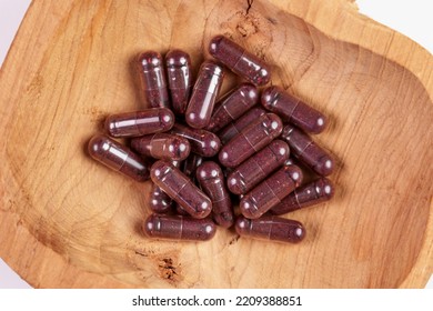 Health Capsules With Bilberry Extract In A Rustic Wooden Bowl. Pills With Dried Blueberry Powder. Alternative Medicine And Nutritional Supplements. Eyesight Support Food Supplement