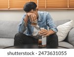 Health care alcoholism drunk, fatigue asian young man drinking beverage on table, alone depressed male drink booze on sofa at home. Treatment of alcohol addiction, suffer abuse problem alcoholism.