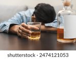 Health care alcoholism drunk, fatigue asian young man holding glass of whiskey, depressed male drink booze, sleep on table at home. Treatment of alcohol addiction, suffer abuse problem alcoholism.