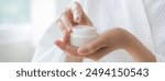 Health care, beauty asian young woman in bathrobe, towel after shower bath, spa relax at home, use finger putting take out moisturizer cream from jar. Skin body moisturizing lotion, routine in morning