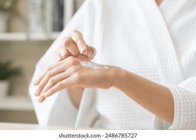 Health care, beauty asian young woman in bathrobe, towel after shower bath, spa relax at home, finger applying moisturizer on her back hand. Skin body cream moisturizing lotion, routine in morning. - Powered by Shutterstock