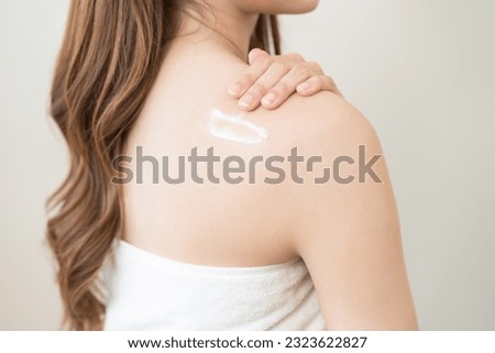 Health care, beauty smile asian young woman, girl wrapped in towel after shower bath, spa relax at home, hand applying body, putting moisturizing lotion on her back. Skincare routine in the morning.