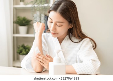 Health care, beauty smile pretty asian young woman in bathrobe, towel after shower bath at home, hand applying, putting moisturizer on her arm. Skin body cream moisturizing lotion, routine in morning. - Powered by Shutterstock