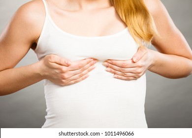 Health care, bosom concept. Young woman wearing tshirt holding hands on breast and pushing them up