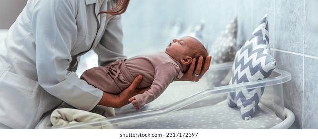 Health care concept. Doctor neonatologist calming down a crying baby holding newborn infant baby girl in hospital. Medical checkup. Young female nurse holding a newborn baby in hospital - Powered by Shutterstock