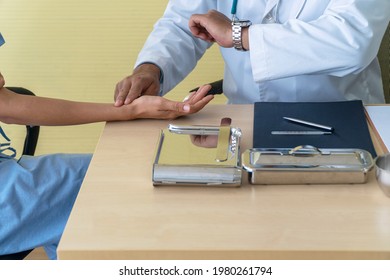 Health Care Concept. Hand Of Professional Doctor With Stethoscope Using Finger Check Pulse Arm Patient Holding Wrist Watch While Sitting Together On Table With Tool In The Clinic.