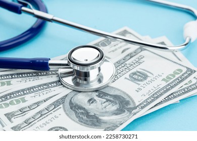 Health care cost concept. US Dollars bills and stethoscope on blue background - Powered by Shutterstock