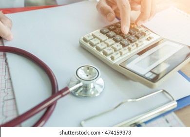Health care costs concept picture :  Hand of doctor used a calculator for medical costs. Stethoscope  and calculator on a medical chart ,symbol for health care costs or medical insurance.