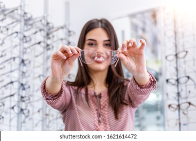 Health care, eyesight and vision concept - happy woman choosing glasses at optics store. Young beautiful girl ar optic store trying on new glasses - Powered by Shutterstock