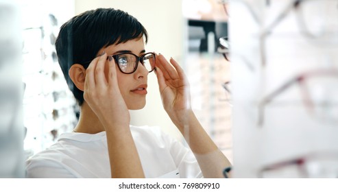 health care, eyesight and vision concept - happy woman choosing glasses at optics store