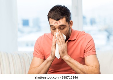health care, flu, allergy, hygiene and people concept -sick man blowing nose to paper napkin at home - Powered by Shutterstock