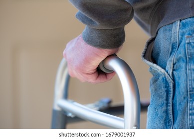 Health Care, Medical Concept Of Elderly Man Using A Walker For Hip Replacement Or Knee Replacement Recovery. Close Up Detail With Blue Jeans And Grey Sweatshirt. 