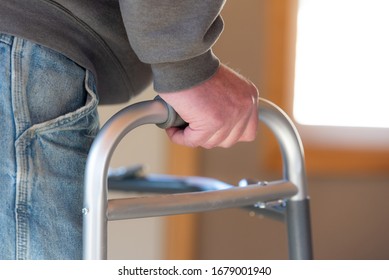 Health Care, Medical Concept Of Elderly Man Using A Walker For Hip Replacement Or Knee Replacement Recovery. Close Up Detail With Blue Jeans And Grey Sweatshirt. 