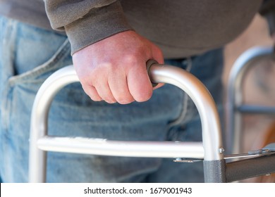 Health Care, Medical Concept Of Elderly Man Using A Walker For Hip Replacement Or Knee Replacement Recovery. Close Up Detail With Blue Jeans And Grey Sweatshirt. 