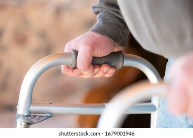 Health Care, Medical Concept Of Elderly Man Using A Walker For Hip Replacement Or Knee Replacement Recovery. Close Up Detail With Blue Jeans And Grey Sweatshirt. 