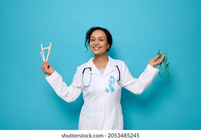 Health Care And Medical Concept, Metabolic Syndrome Disease. Doctor Nutritionist Endocrinologist Wearing A Blue Diabetes Awareness Ribbon, Holds A Caliper And Measuring Tape Against Colored Background