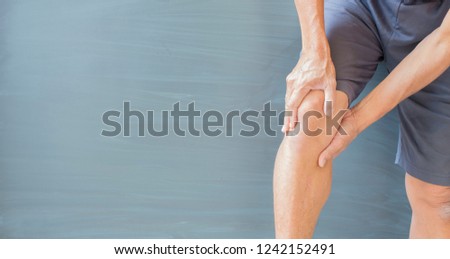 Health Care  Medical,An old man's hand holds his own knee muscles with injuries and rheumatoid arthritis. On gray background there is space.