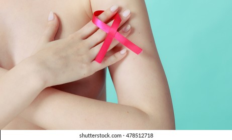 Health care, medicine and breast cancer awareness concept. Young naked woman with pink ribbon symbol covering her chest, on blue