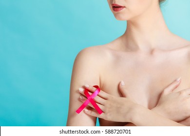 Health care, medicine and breast cancer awareness concept. Young naked woman with pink ribbon symbol covering her chest, on blue